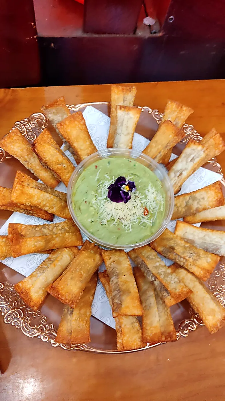 Tequeños servidos alrededor de un bol de guacamole